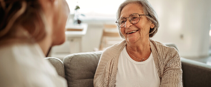 older woman smiling at a younger woman on a couch medicare
