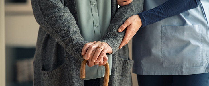 young woman holding older womans arm who is holding a cane nursing home care and resident rights