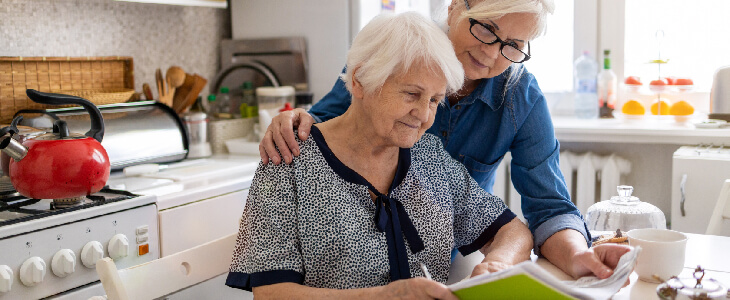 woman looking over older womans shoulder reading paperwork elder law